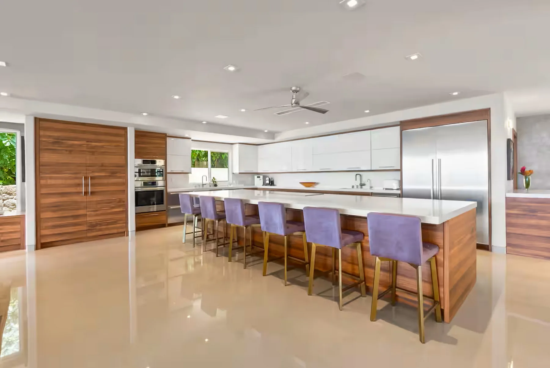 Una cocina luminosa con una isla larga y asientos morados.