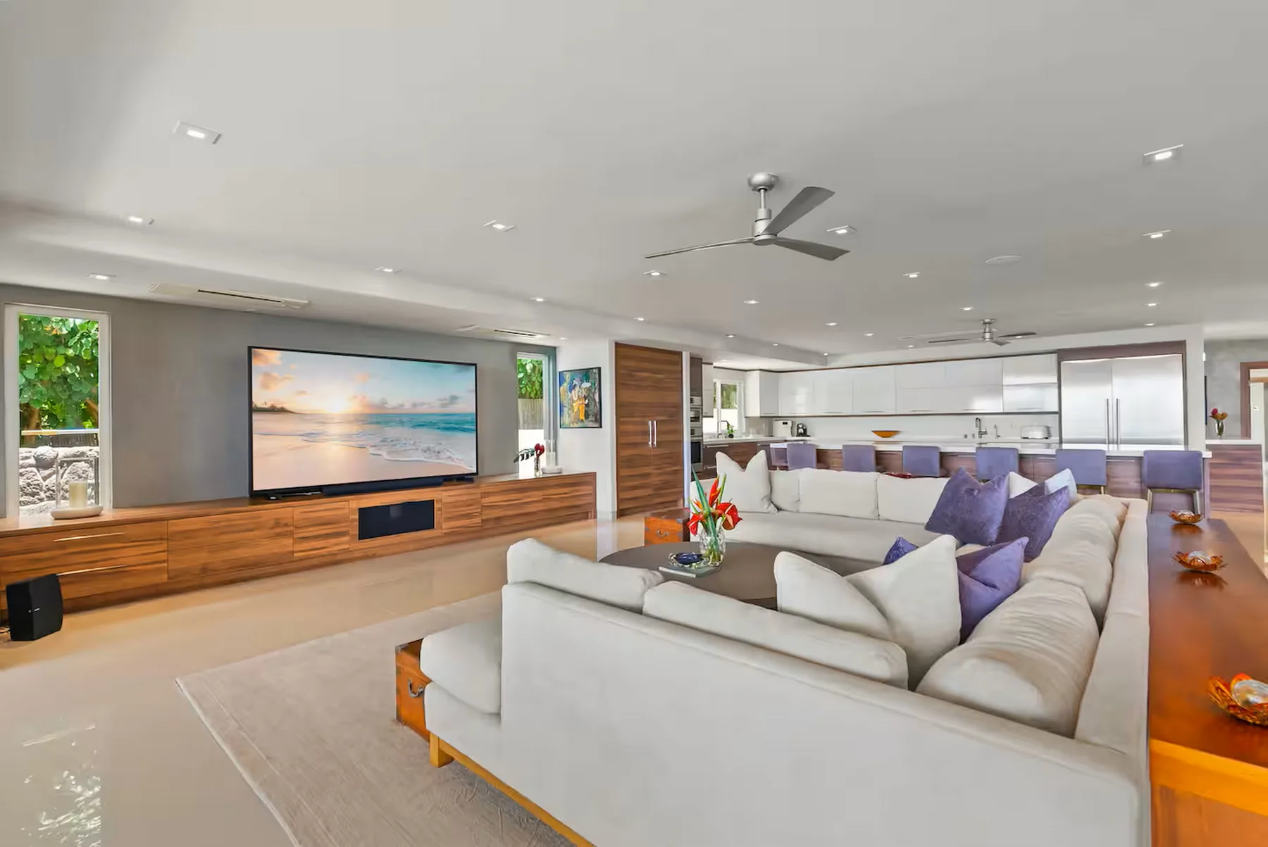 Una luminosa sala de estar de planta abierta con un televisor grande y zona de descanso.