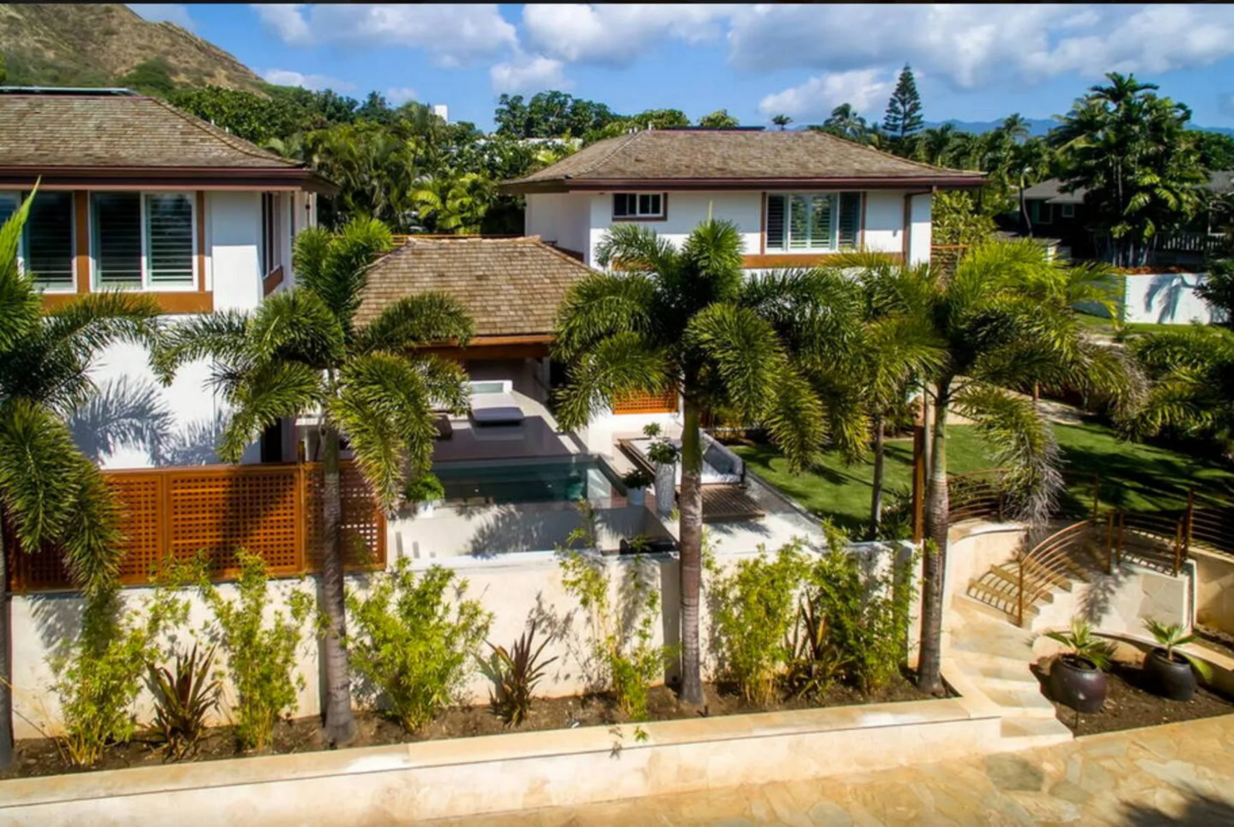Una propiedad residencial ajardinada con varias casas, palmeras y una piscina.