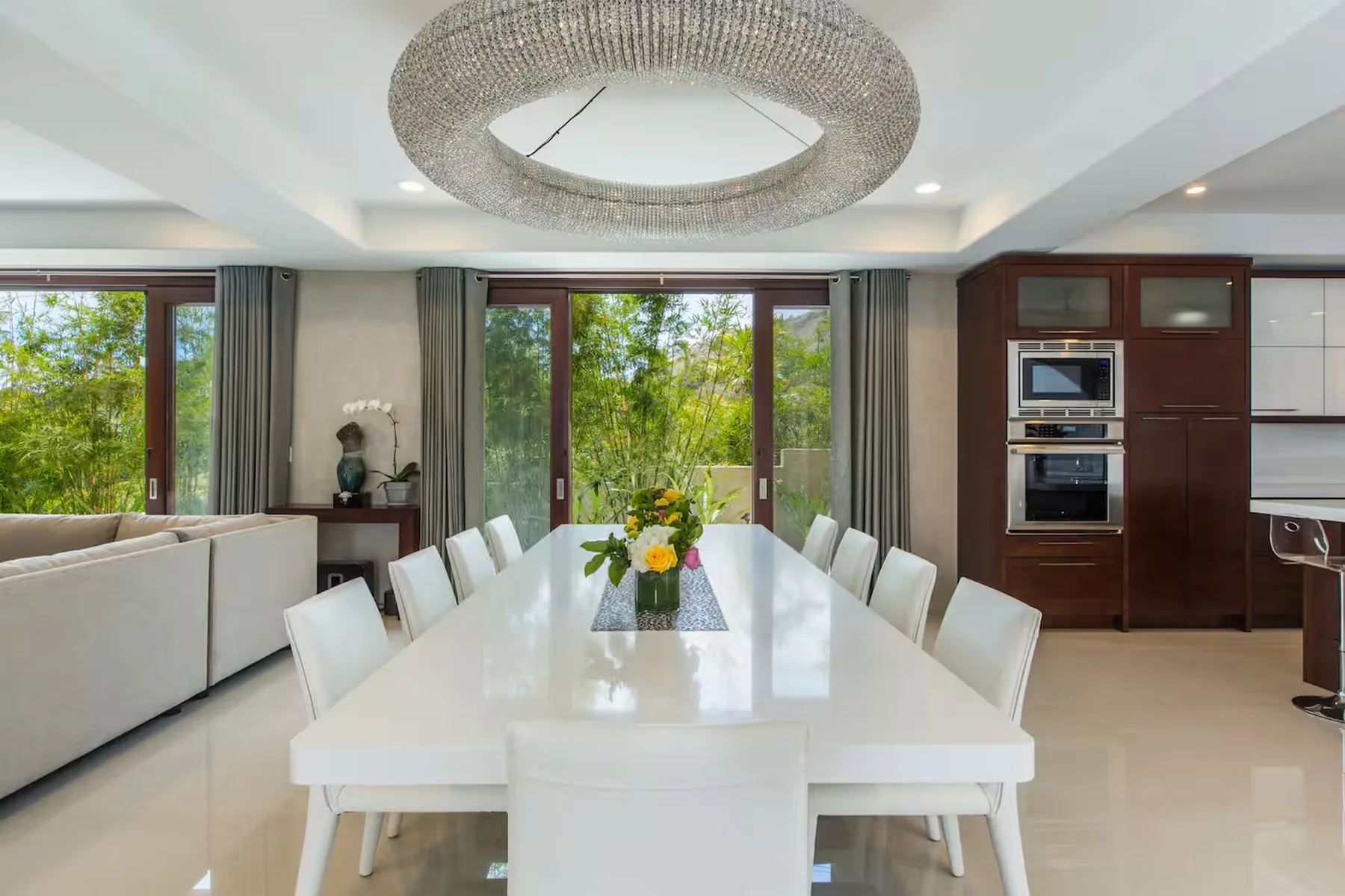 Un comedor luminoso con una larga mesa blanca junto a grandes ventanales.