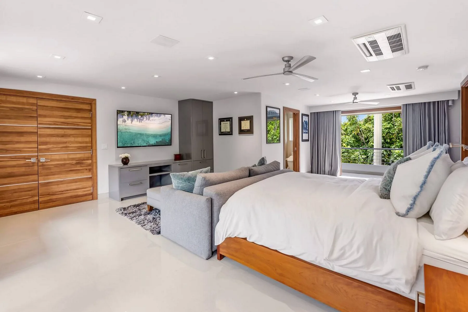 Un dormitorio luminoso con una cama grande, zona de estar y puertas corredizas de vidrio.