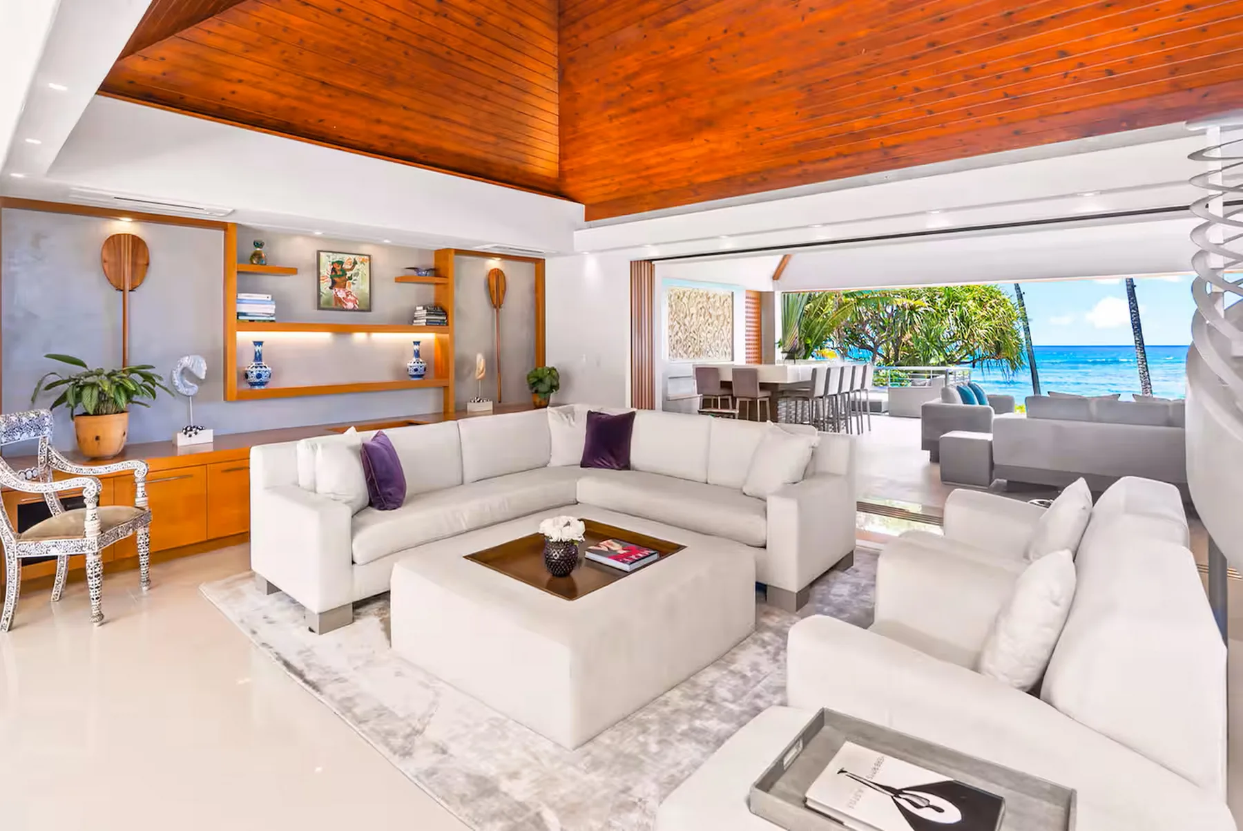 A bright living room with white seating and an open view toward the ocean.