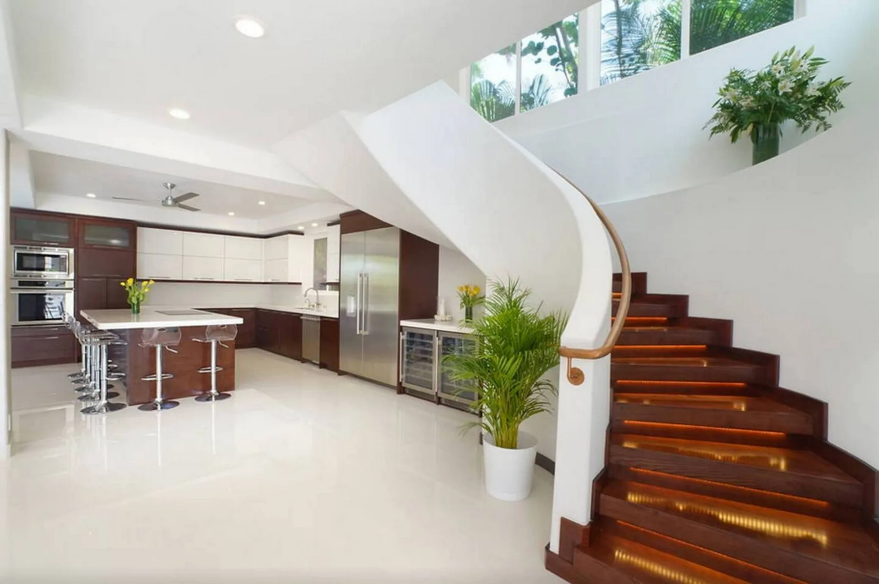 Una cocina y comedor de planta abierta y luminosos están junto a una escalera curva.