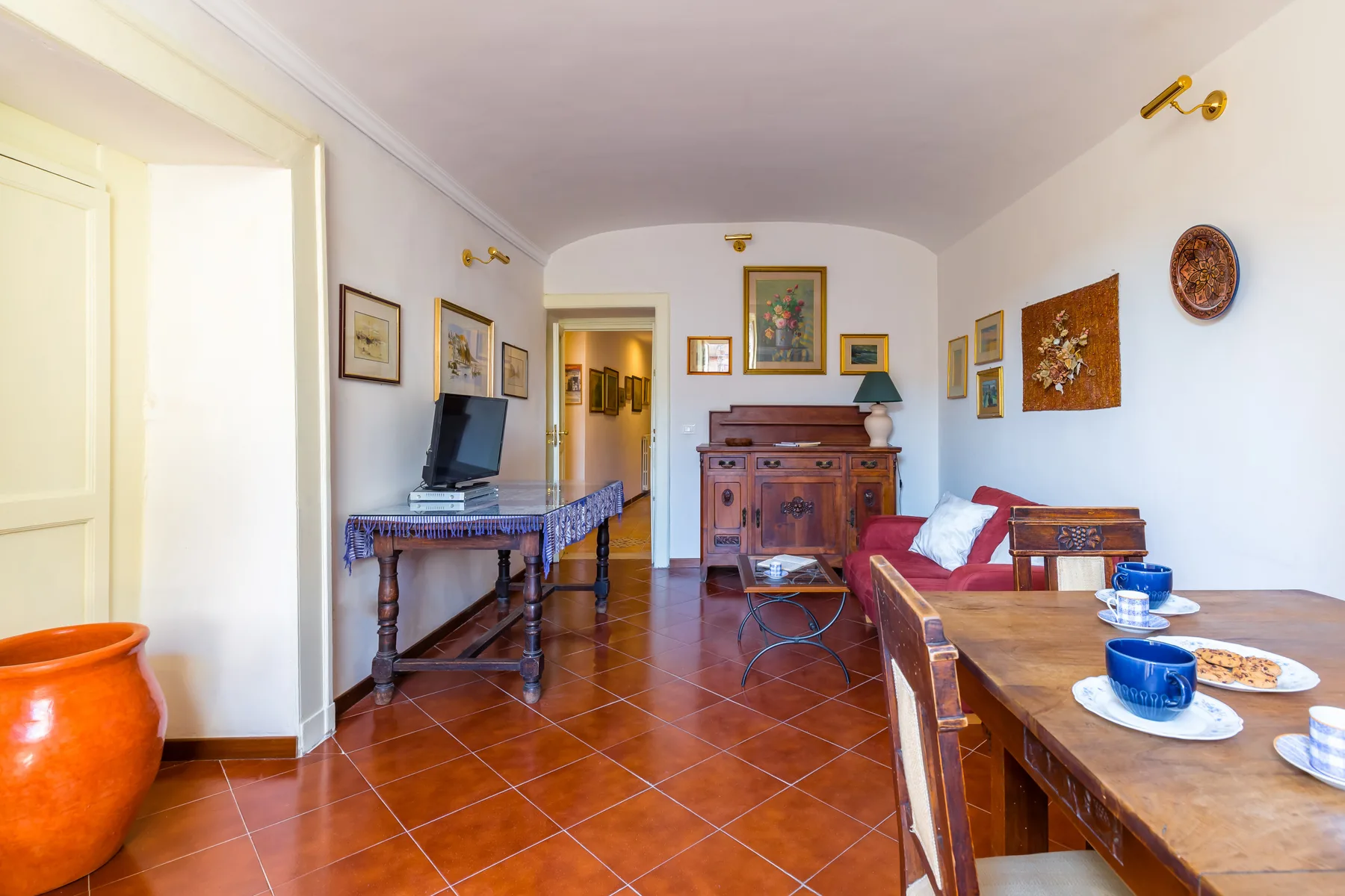 A dining and sitting room with a wooden table and red seating.