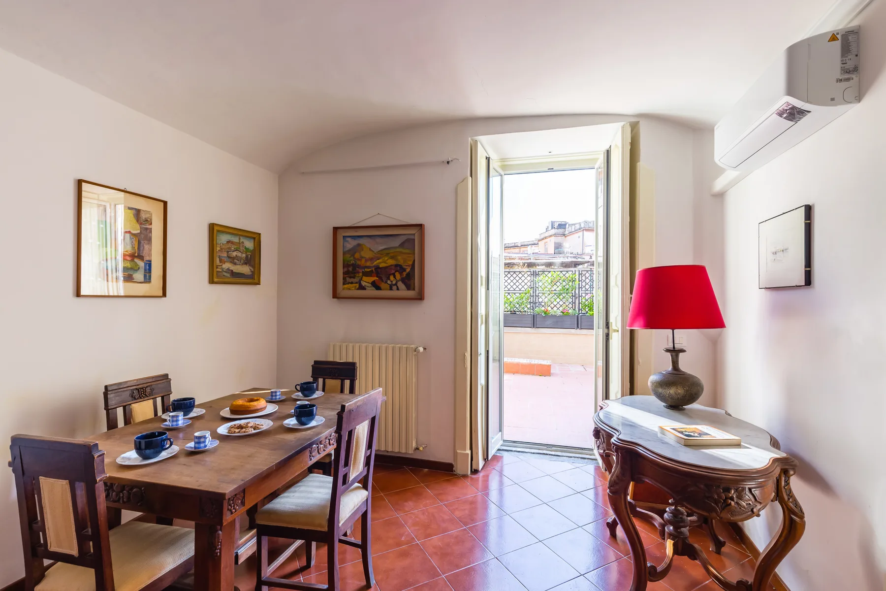 A dining room with a wooden table and an open doorway leading to a balcony.