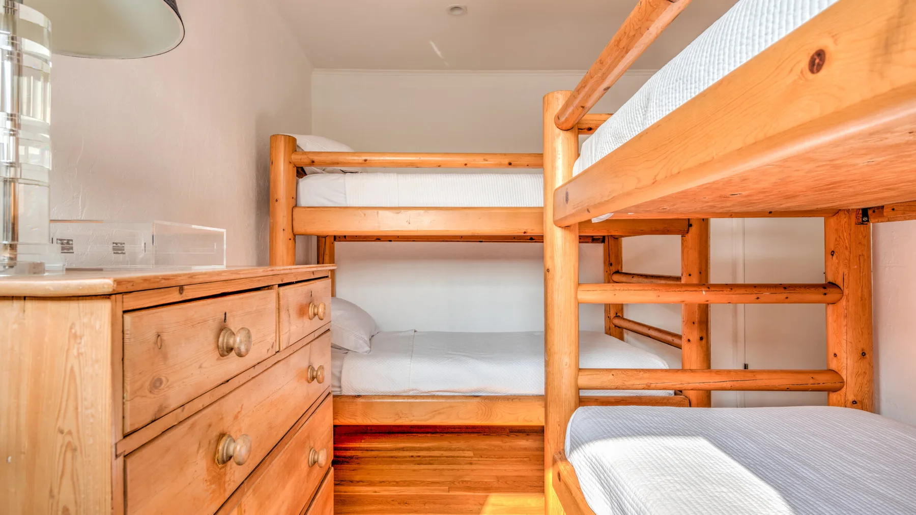 Un dormitorio con literas de madera y una cómoda de madera.