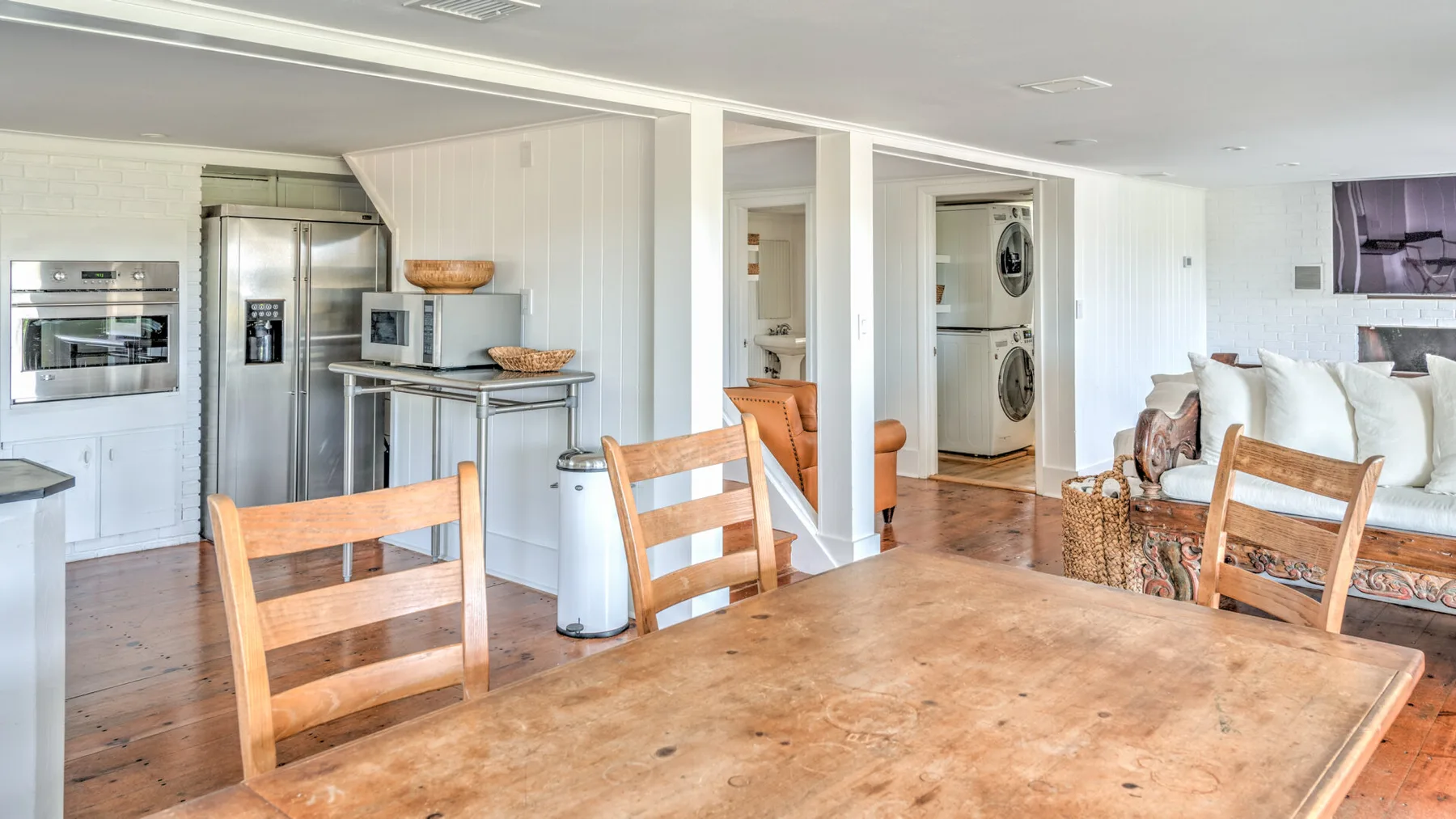 Una cocina abierta y comedor con una mesa grande de madera y electrodomésticos de acero inoxidable.