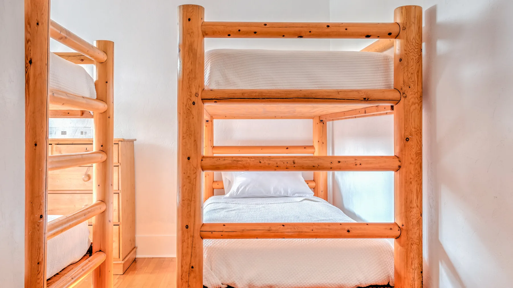 Un dormitorio con literas de madera y ropa de cama blanca.