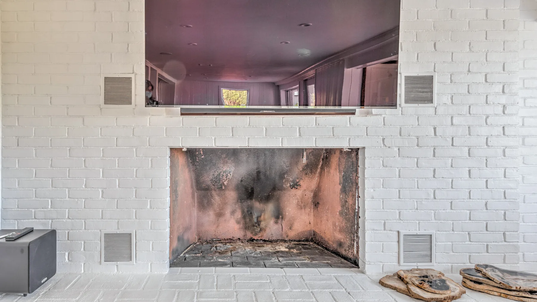 A white brick fireplace with a dark, soot-marked interior.