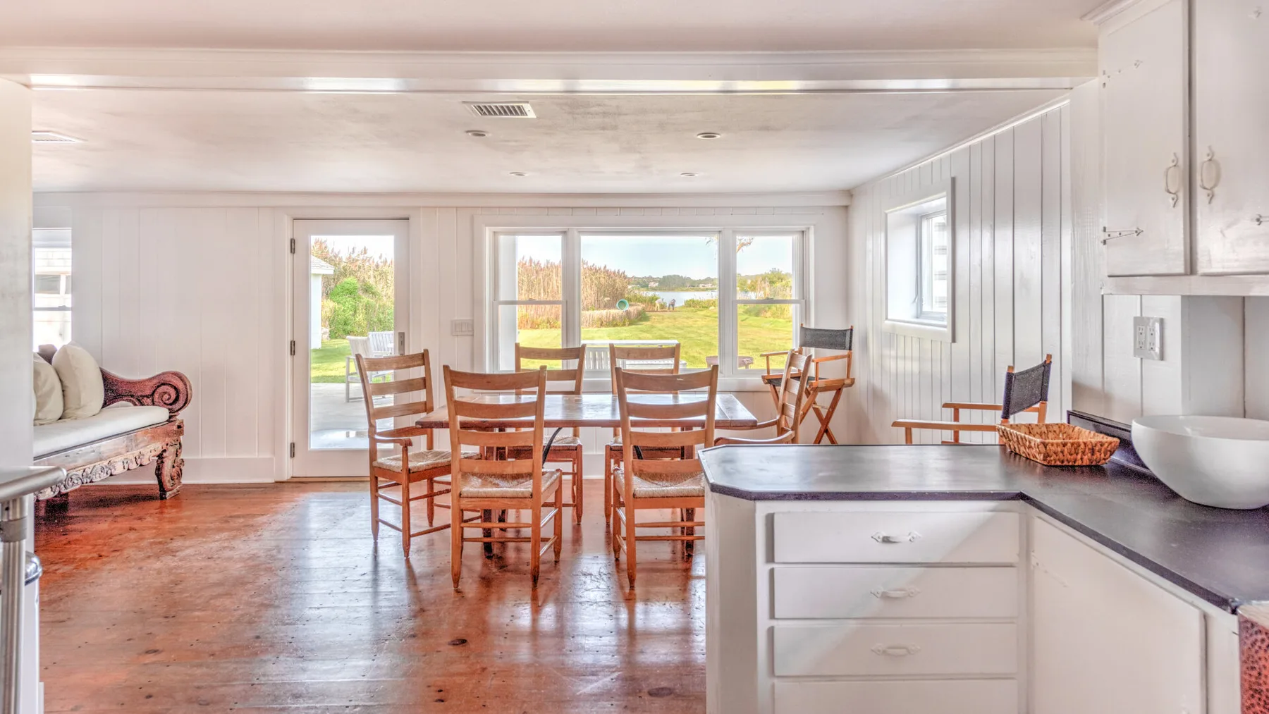 Un comedor luminoso con una mesa de madera y sillas junto a una encimera de cocina.
