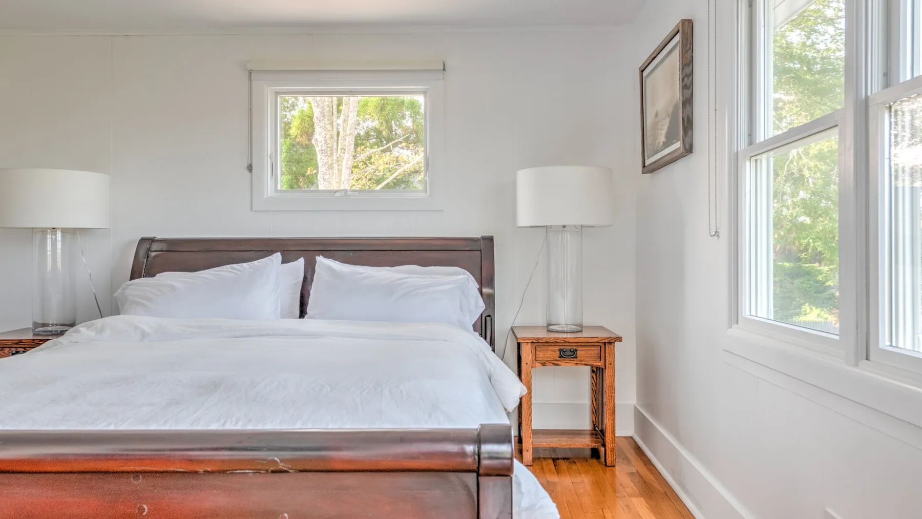 Un dormitorio luminoso con una cama y ventanas que dan a zonas verdes.