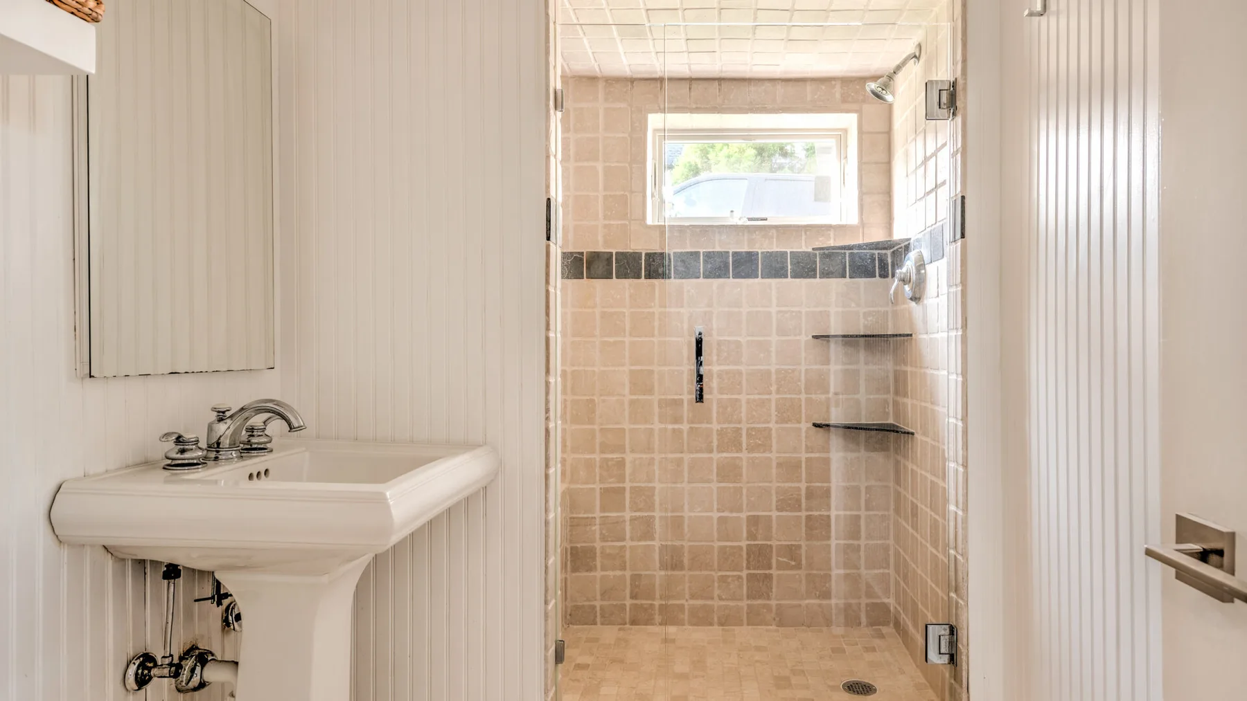 Un baño con un lavabo junto a una zona de ducha con azulejos.