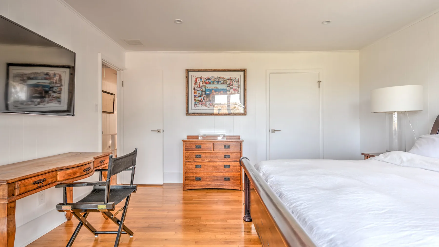 Un dormitorio luminoso con una cama de madera, una cómoda y un escritorio.