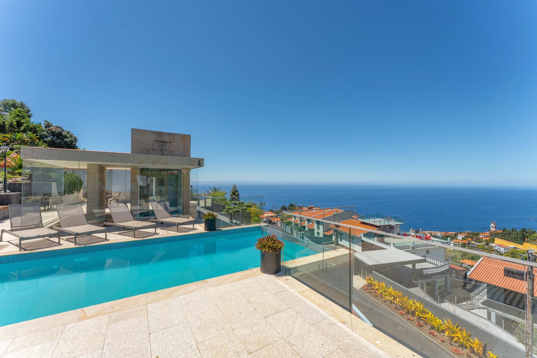 A rooftop swimming pool overlooks coastal buildings and the sea.