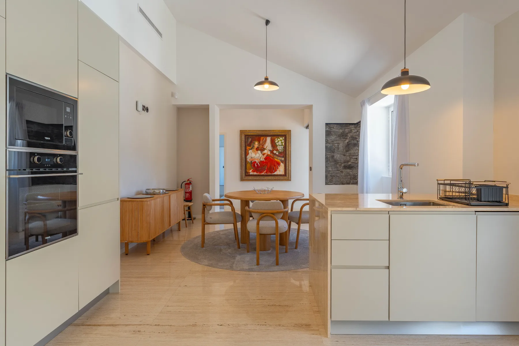A bright kitchen and dining area with a table beneath pendant lights.