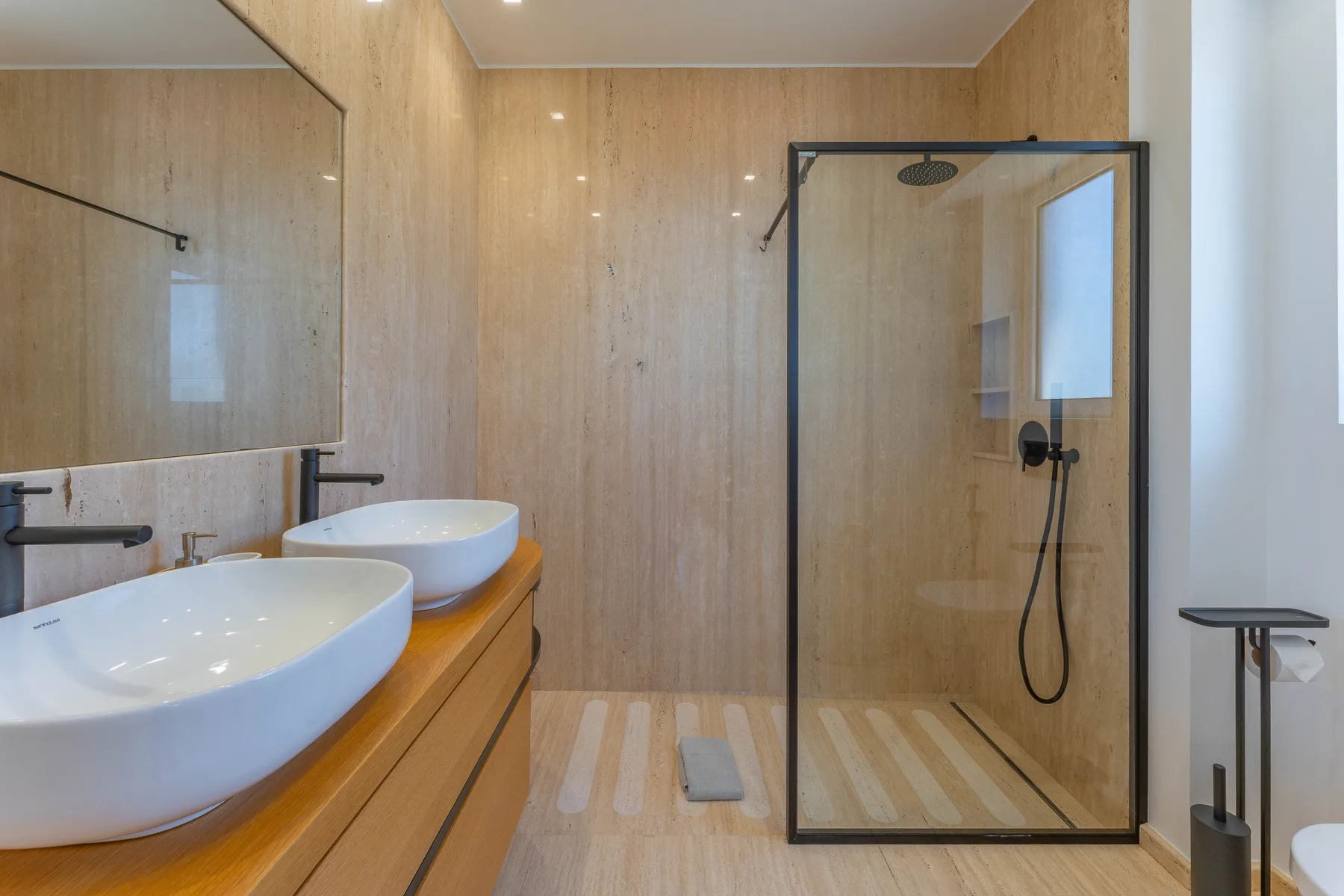 A modern bathroom with a double sink and glass shower.
