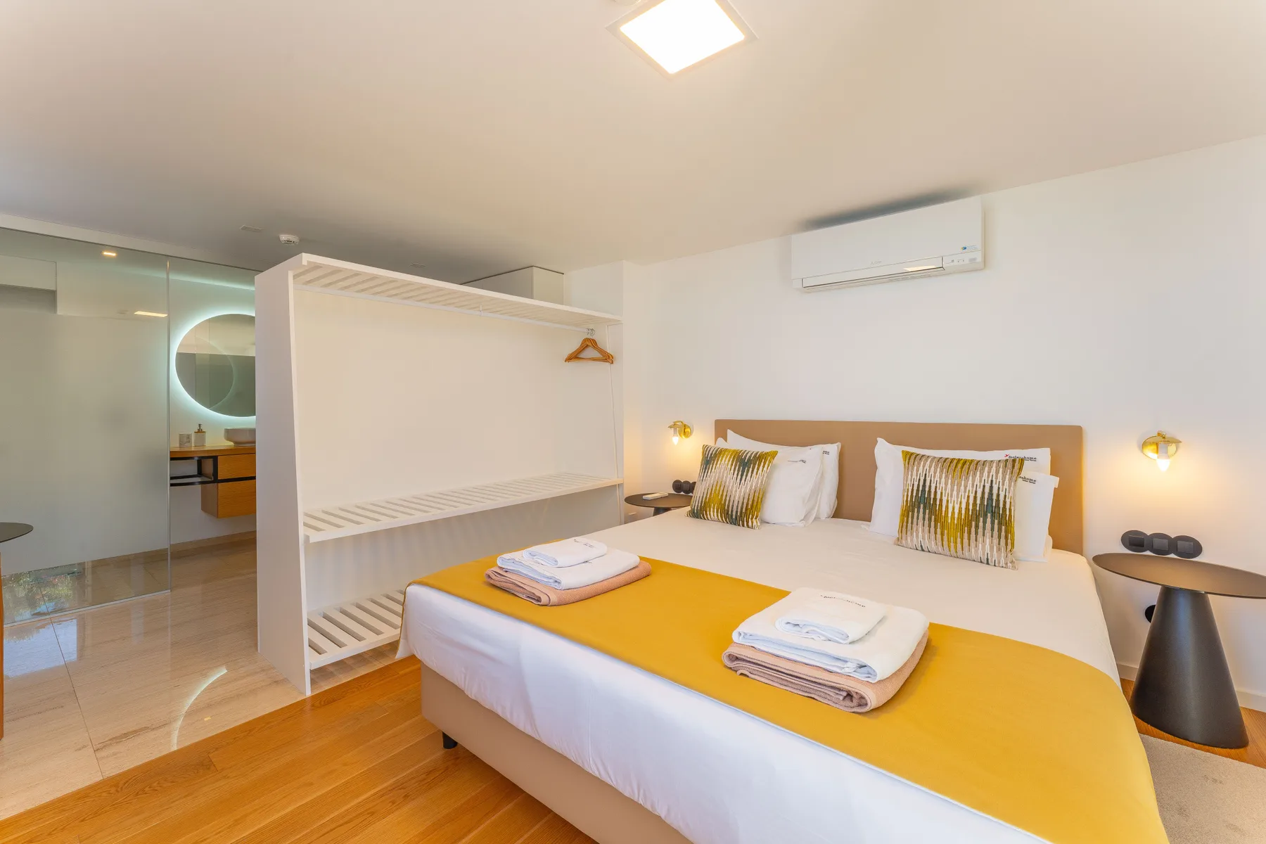 A bright bedroom with a large bed, yellow bedding, and mirrored closet doors.