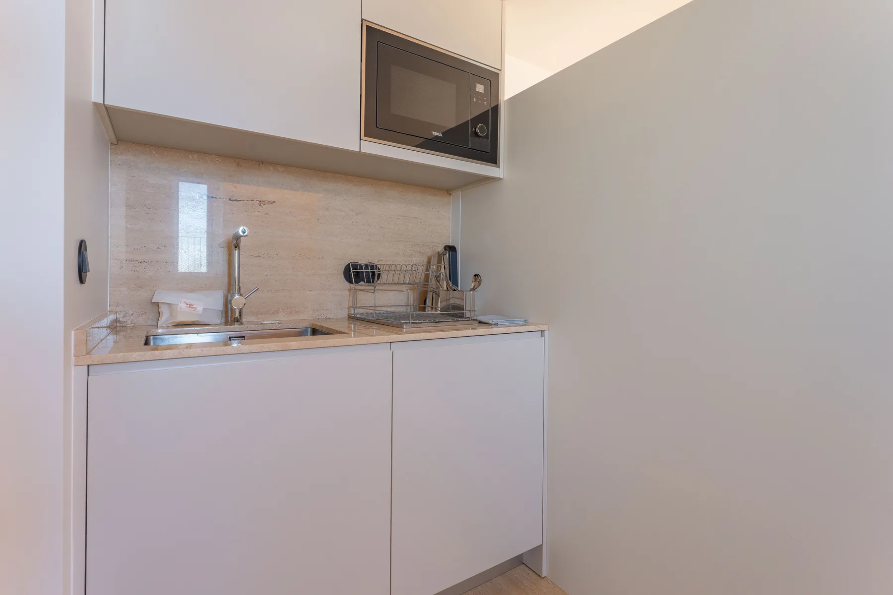A compact kitchen with a sink, cooktop, and microwave.