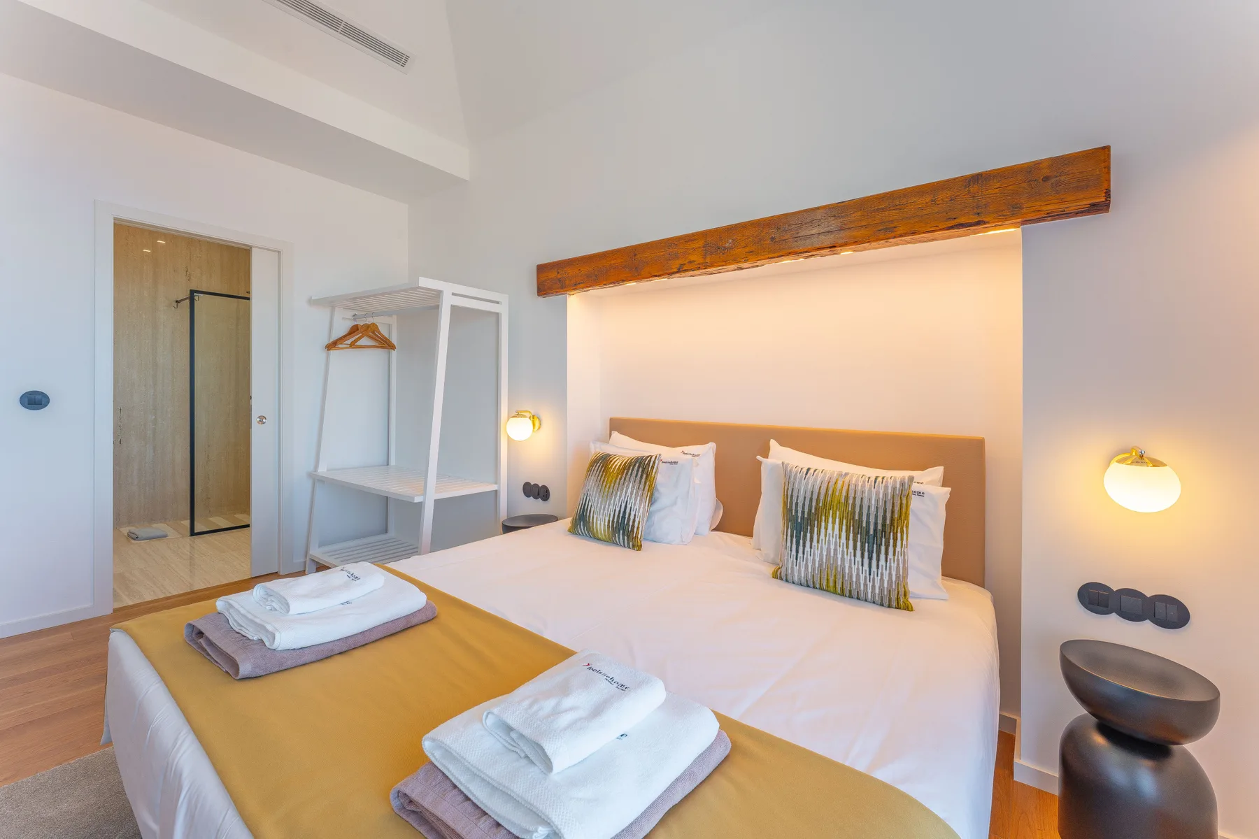 A bedroom with a neatly made bed and towels folded on top.