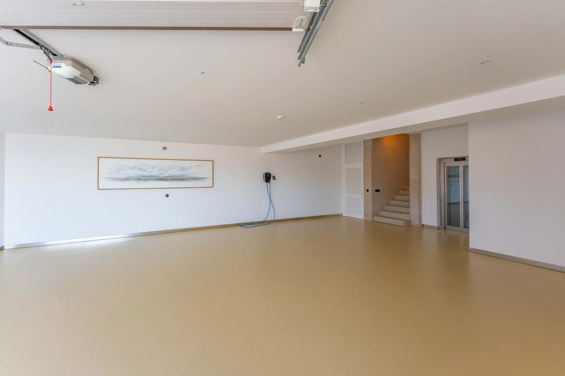 A spacious, empty room with a framed picture and a staircase.