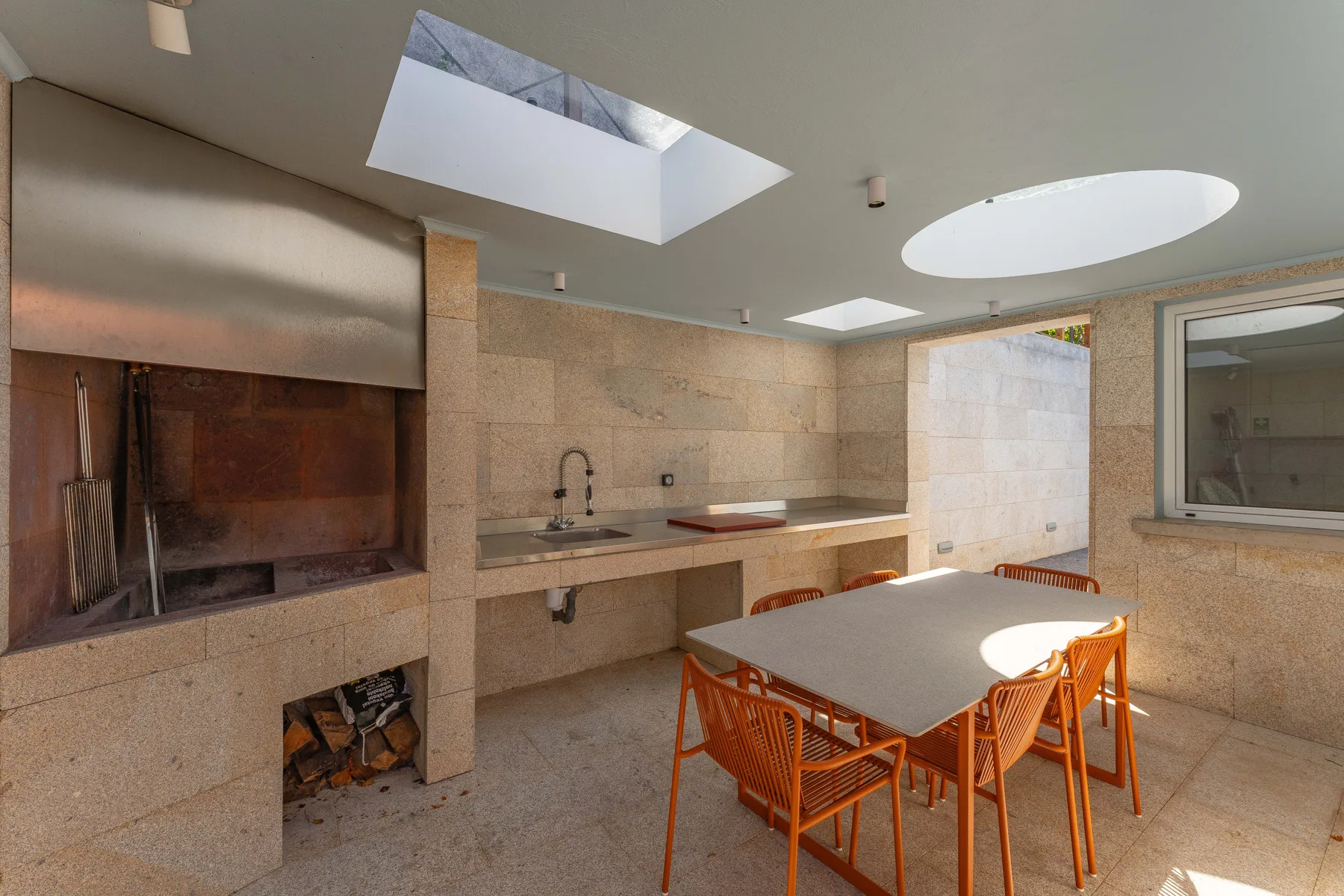 An indoor dining area with orange seating beside a stone counter and fireplace.
