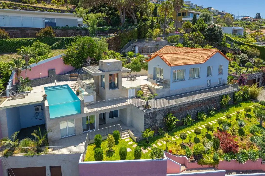 A hillside house with a swimming pool and landscaped garden.