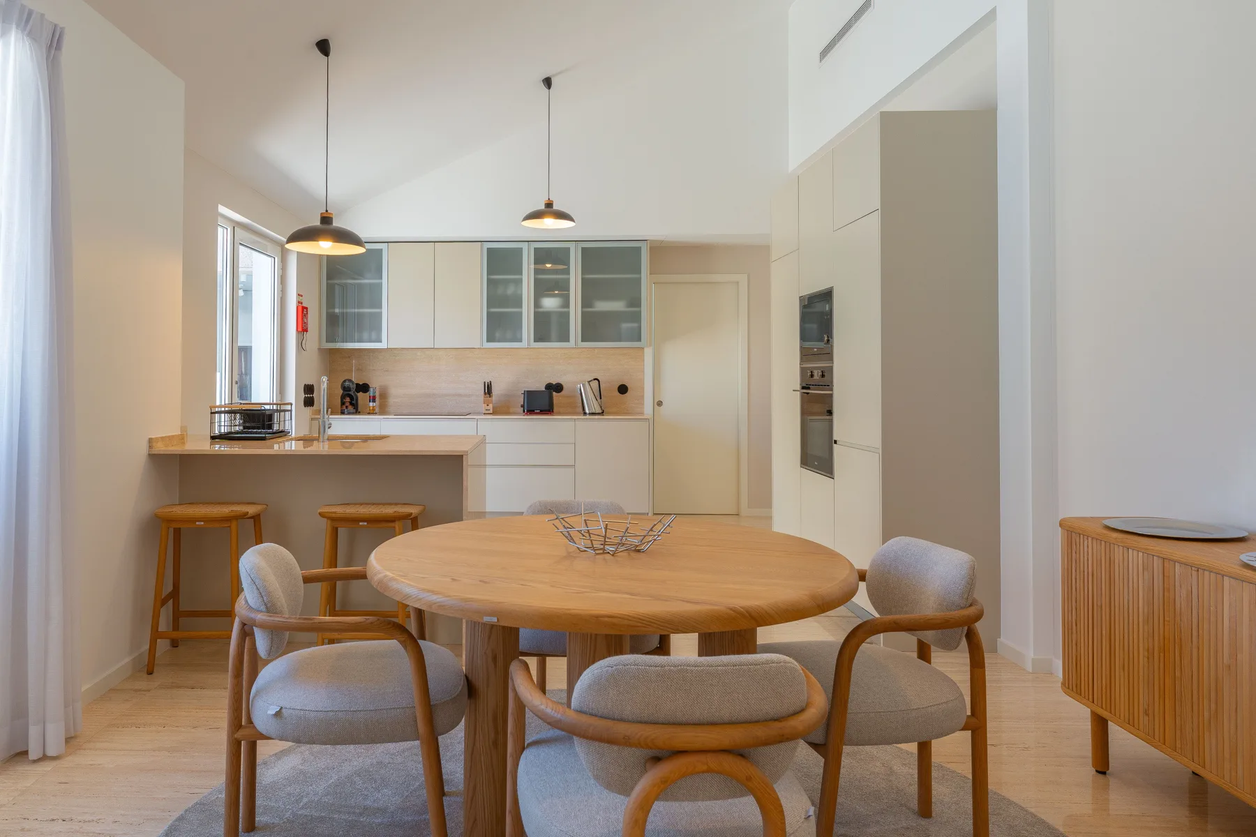 A dining area with a round table and an open kitchen.