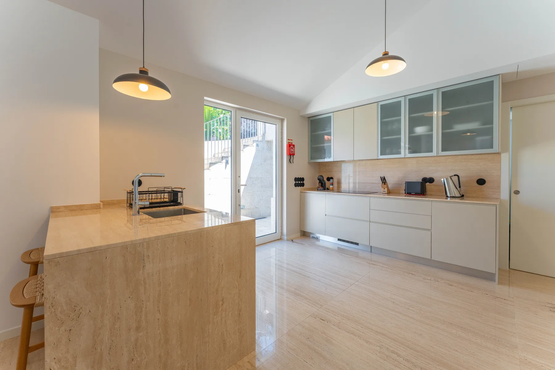A bright kitchen with an island, pale cabinetry, and glass-front upper cabinets.