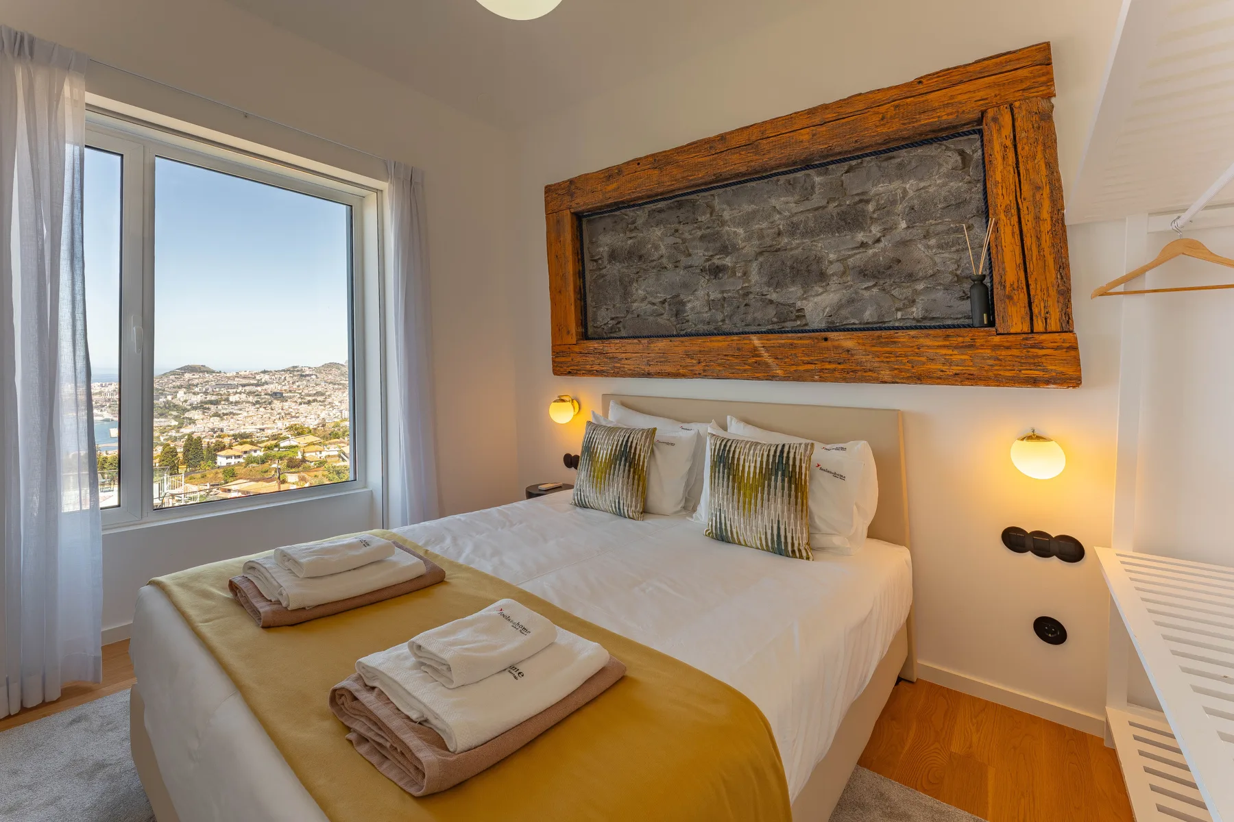 A bedroom with a bed and a window overlooking the surrounding city.