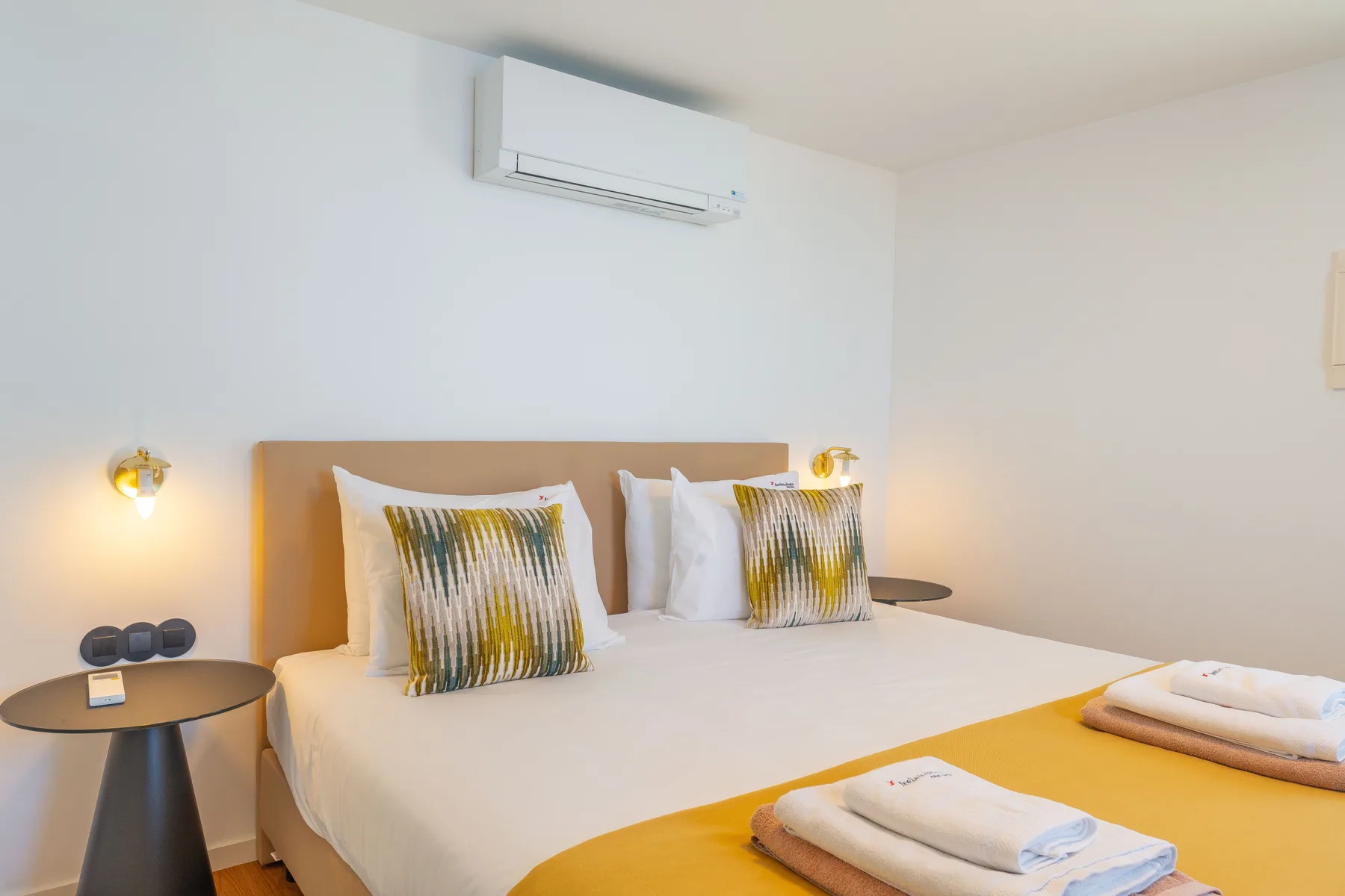 A bright bedroom with a double bed, decorative pillows, and bedside tables.