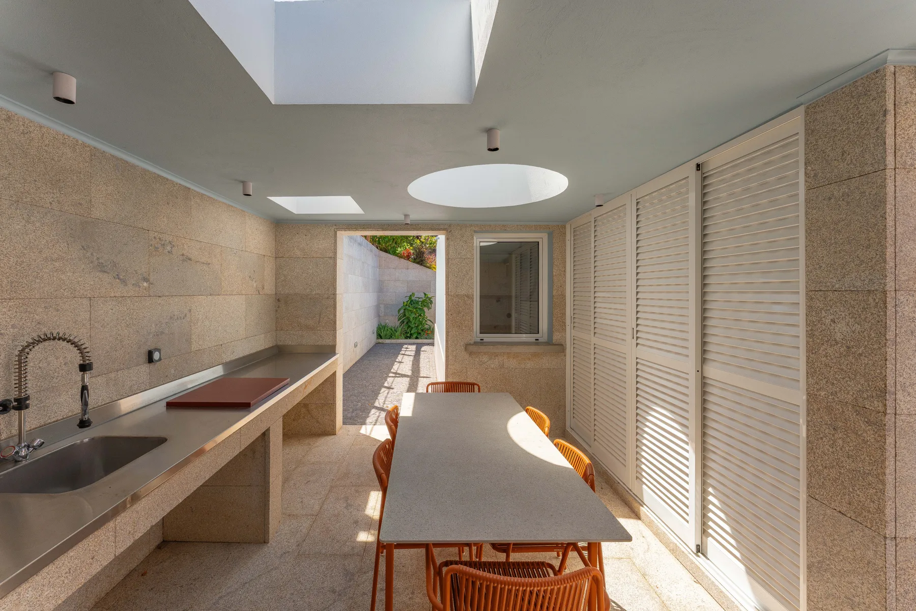 A bright dining area with a long table beside a counter and sink.