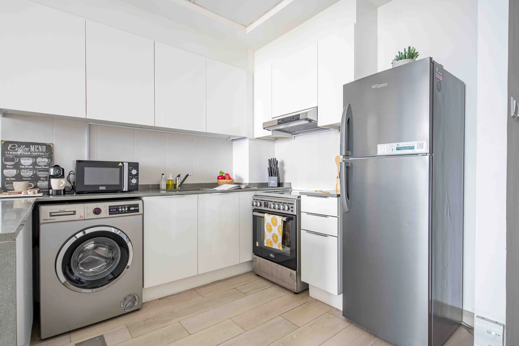 A bright kitchen with white cabinets, a refrigerator, and a washing machine.