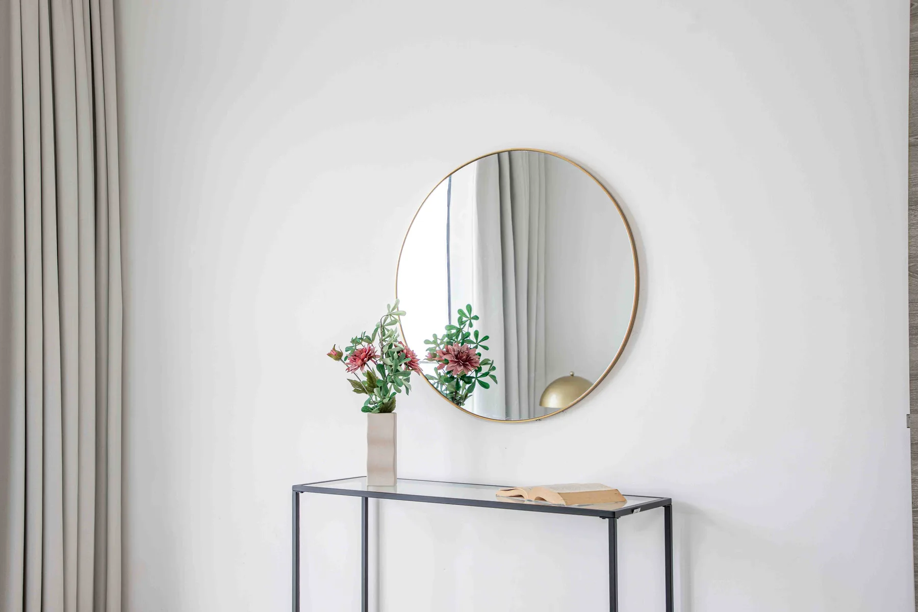 A bright room with a round mirror and a narrow table against the wall.