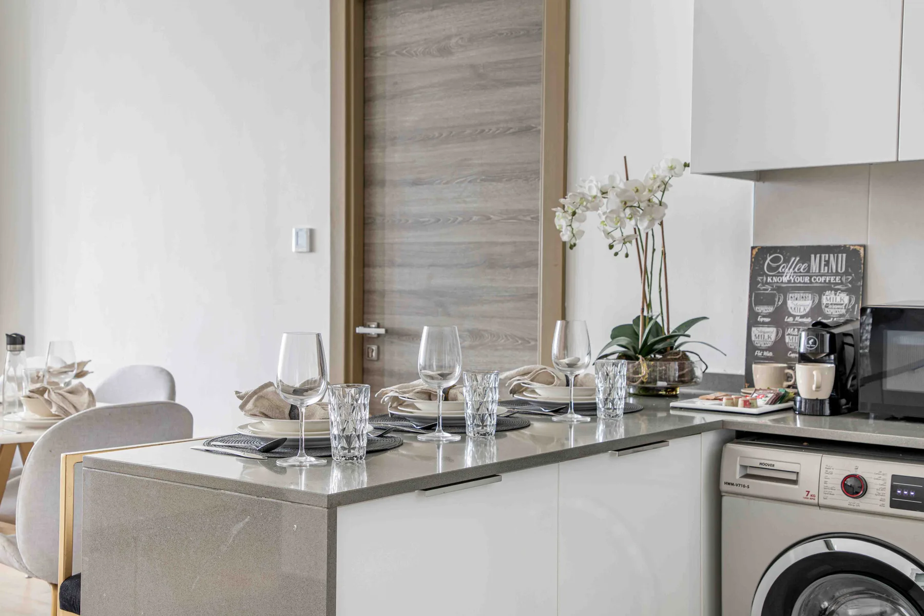 A modern dining area beside a kitchen counter with a washing machine.