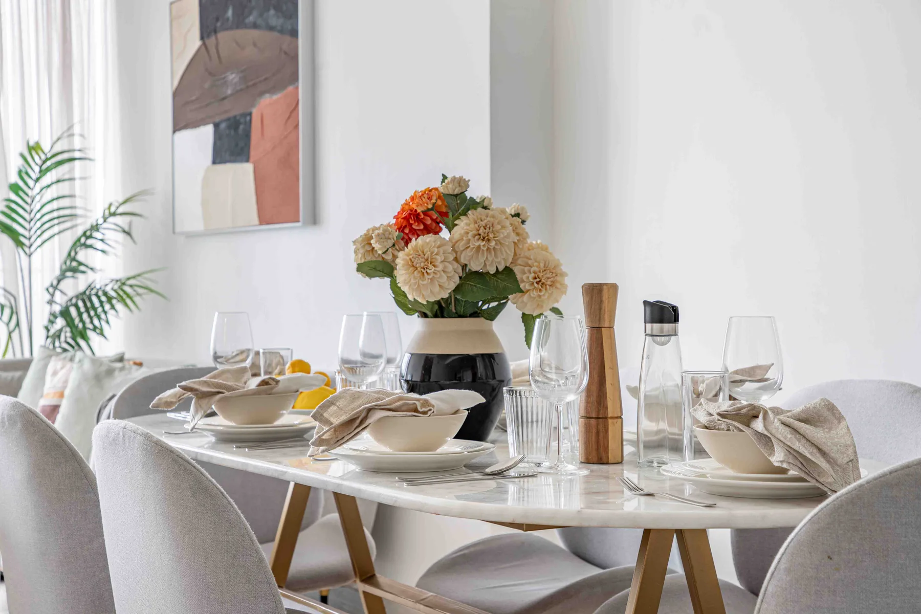 A dining table is set with plates, glassware, and a floral centerpiece.