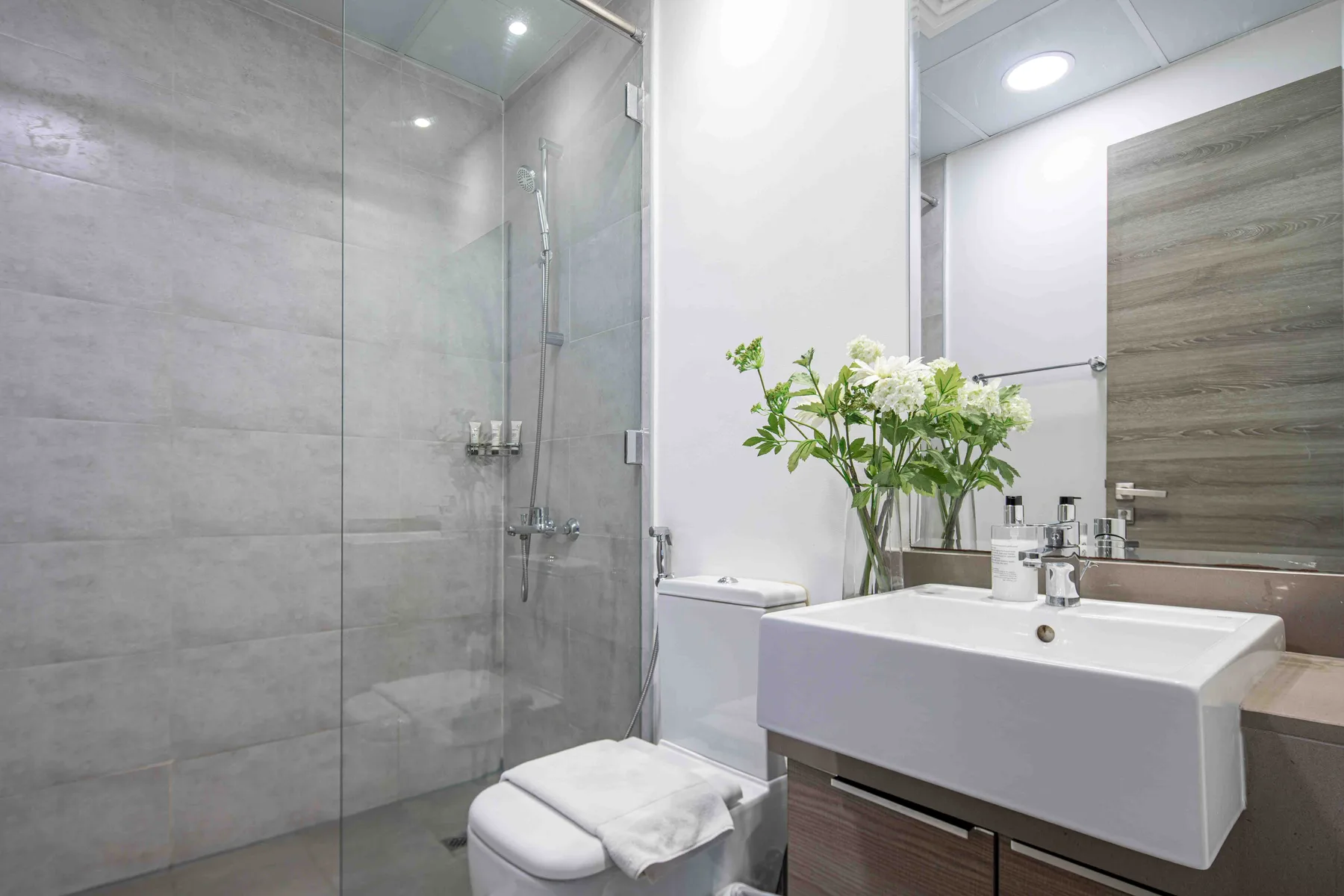 A modern bathroom with a glass shower and a white sink.