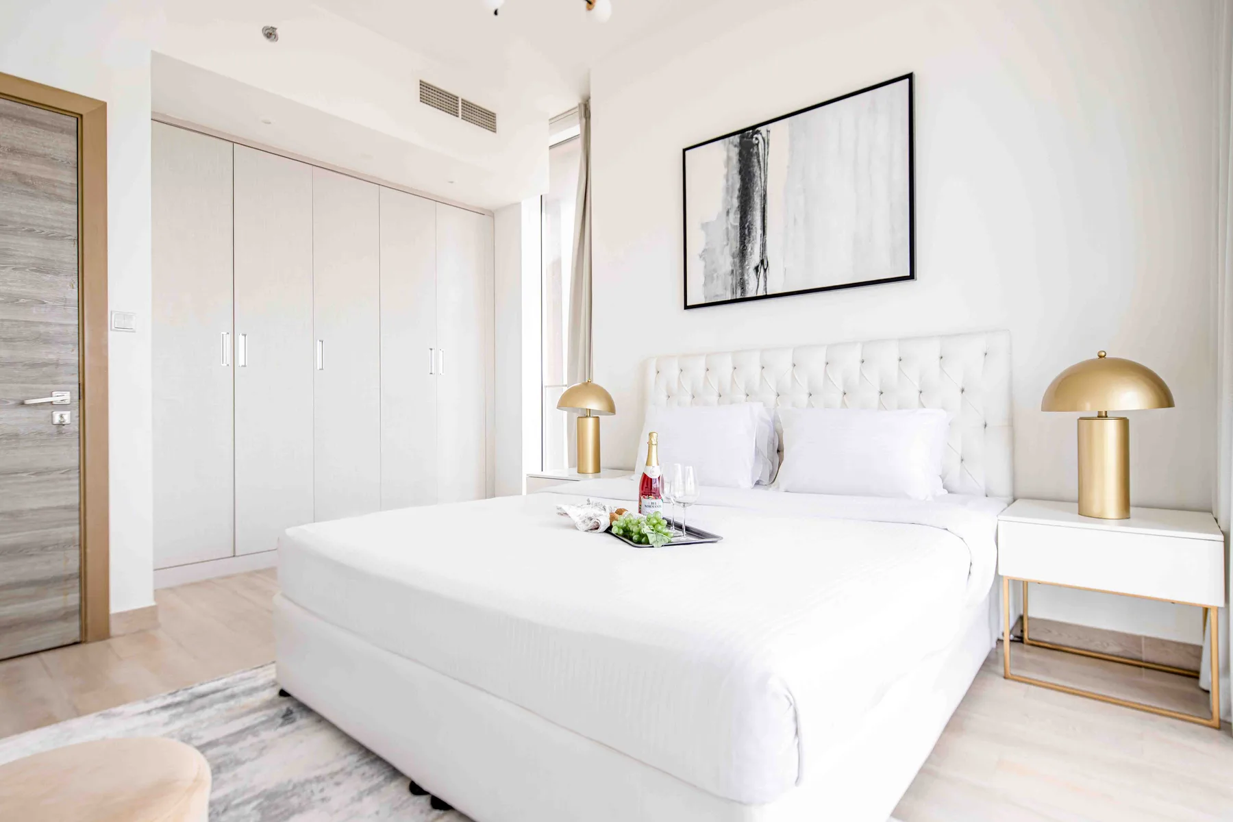 A bright bedroom with a white bed, bedside tables, and framed wall art.