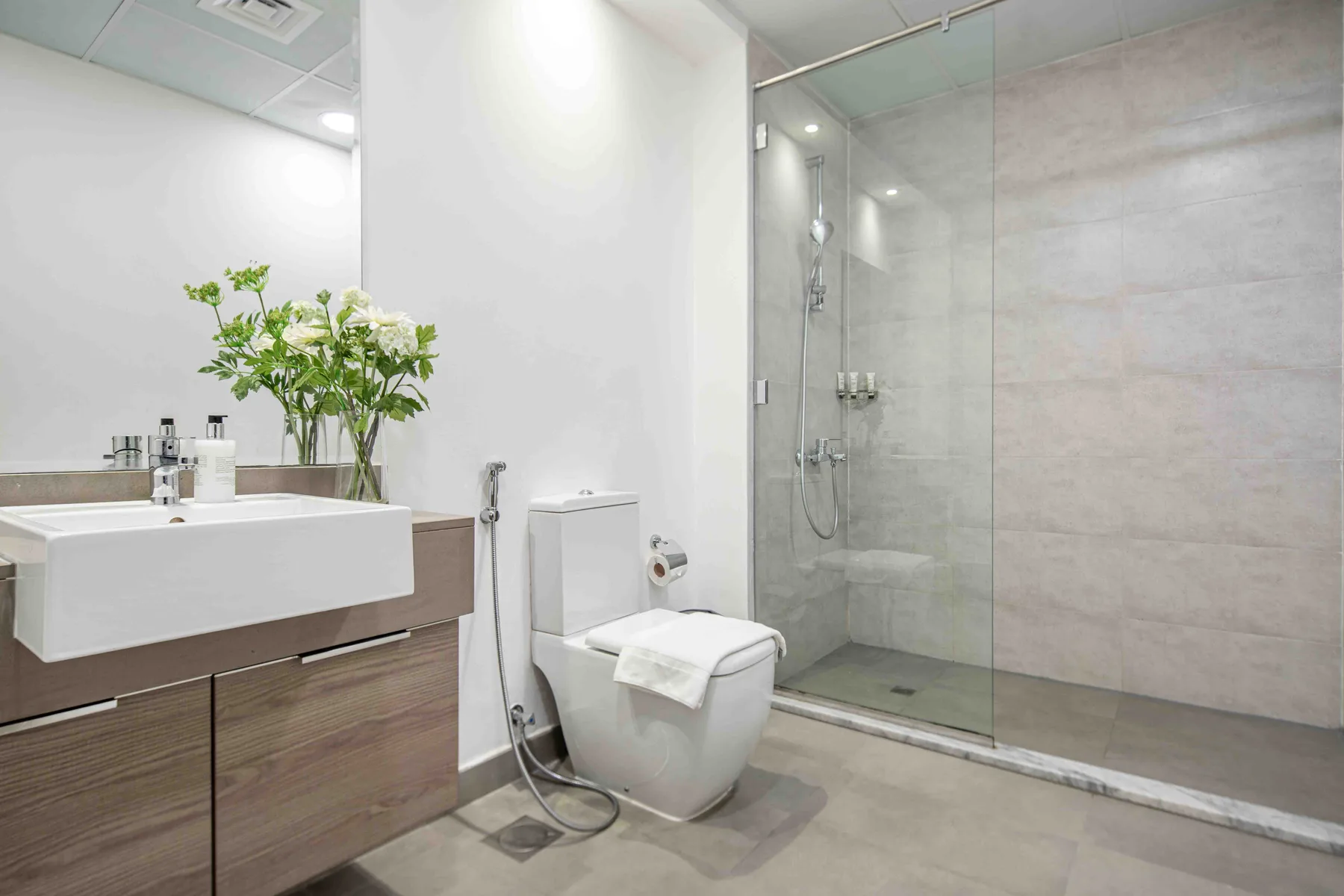 A modern bathroom with a vanity, toilet, and glass-enclosed shower.