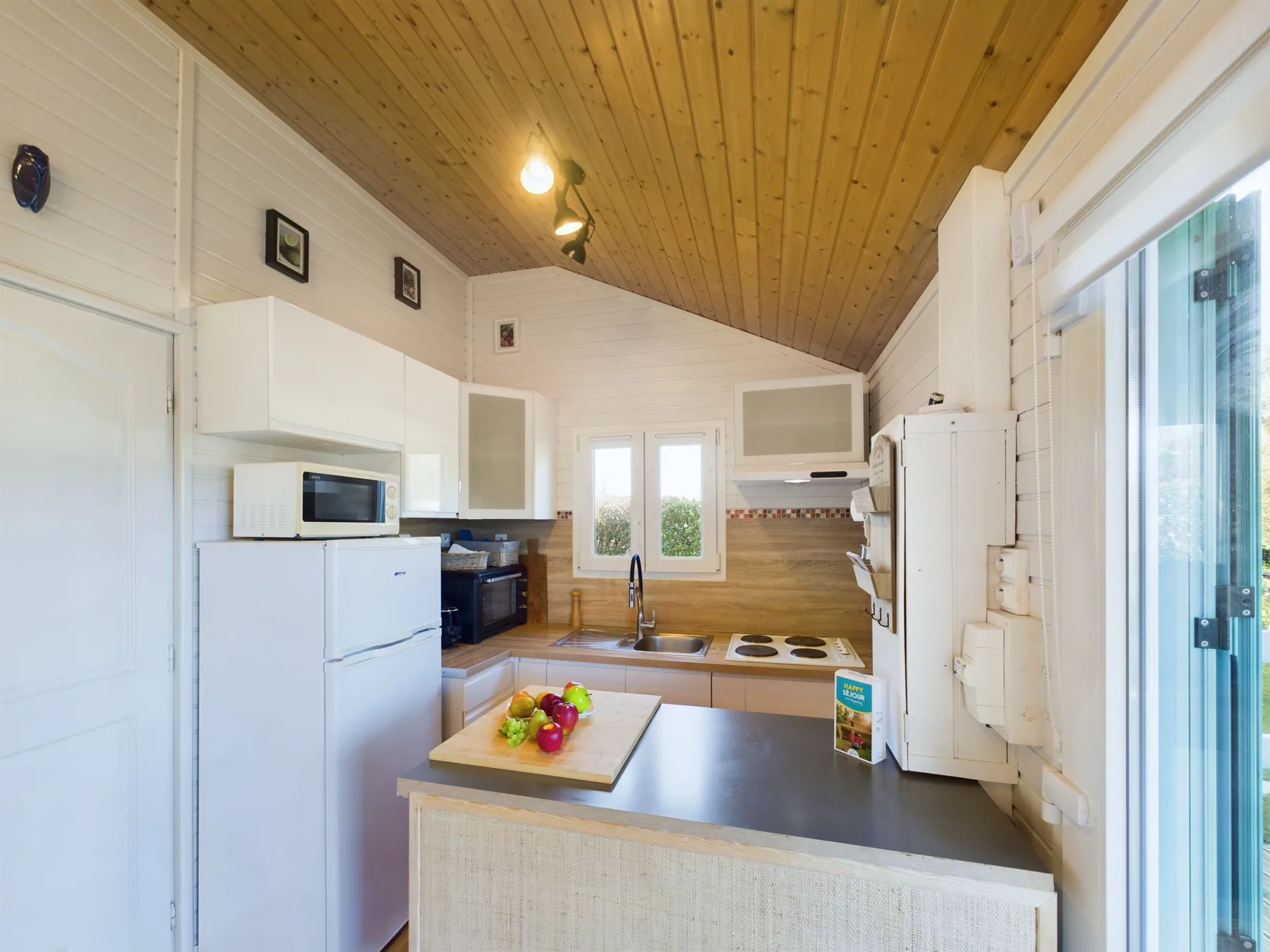 A compact kitchen with white cabinets, a countertop, and a window.