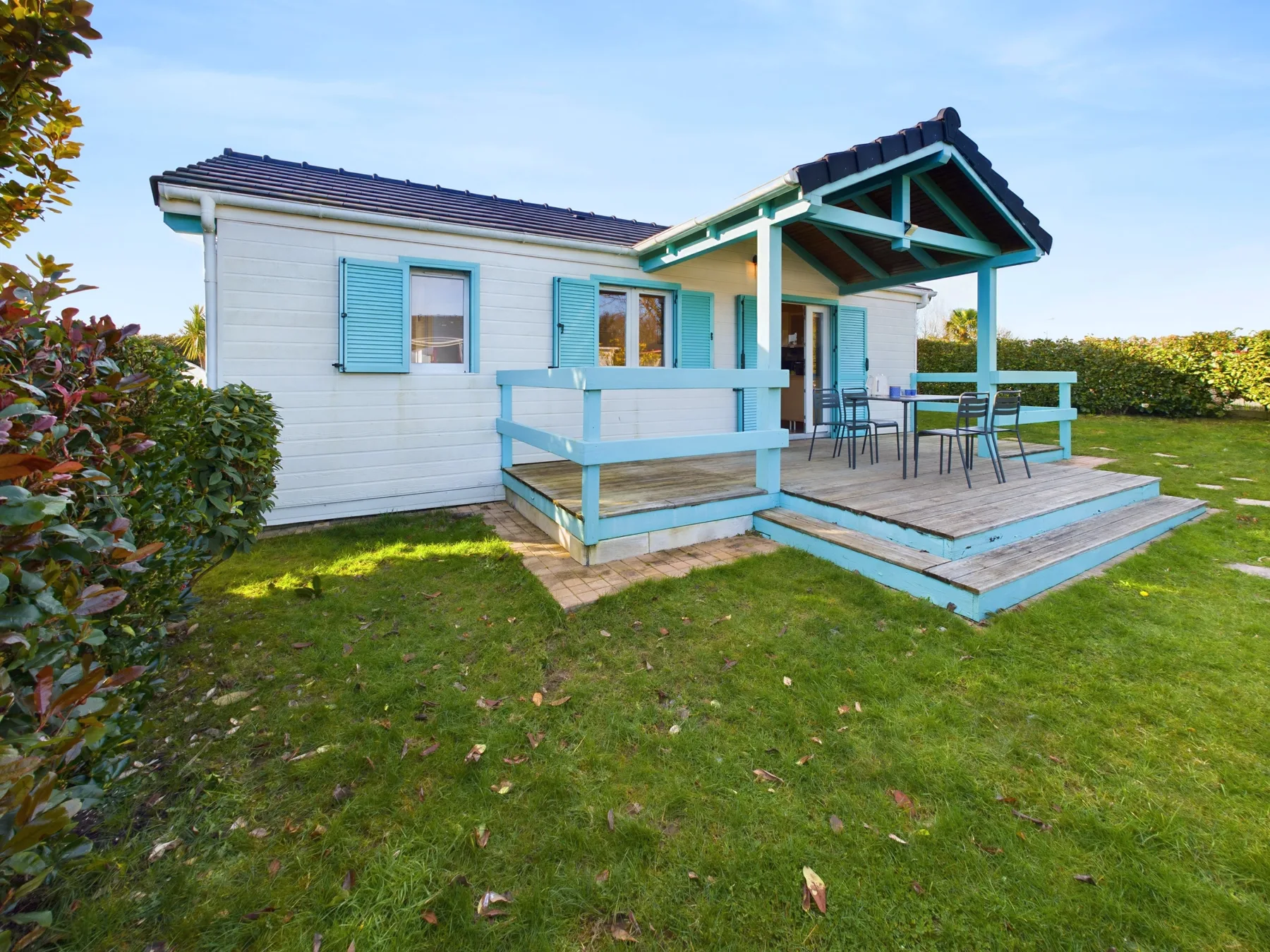 A bungalow with a raised wooden deck and outdoor seating.