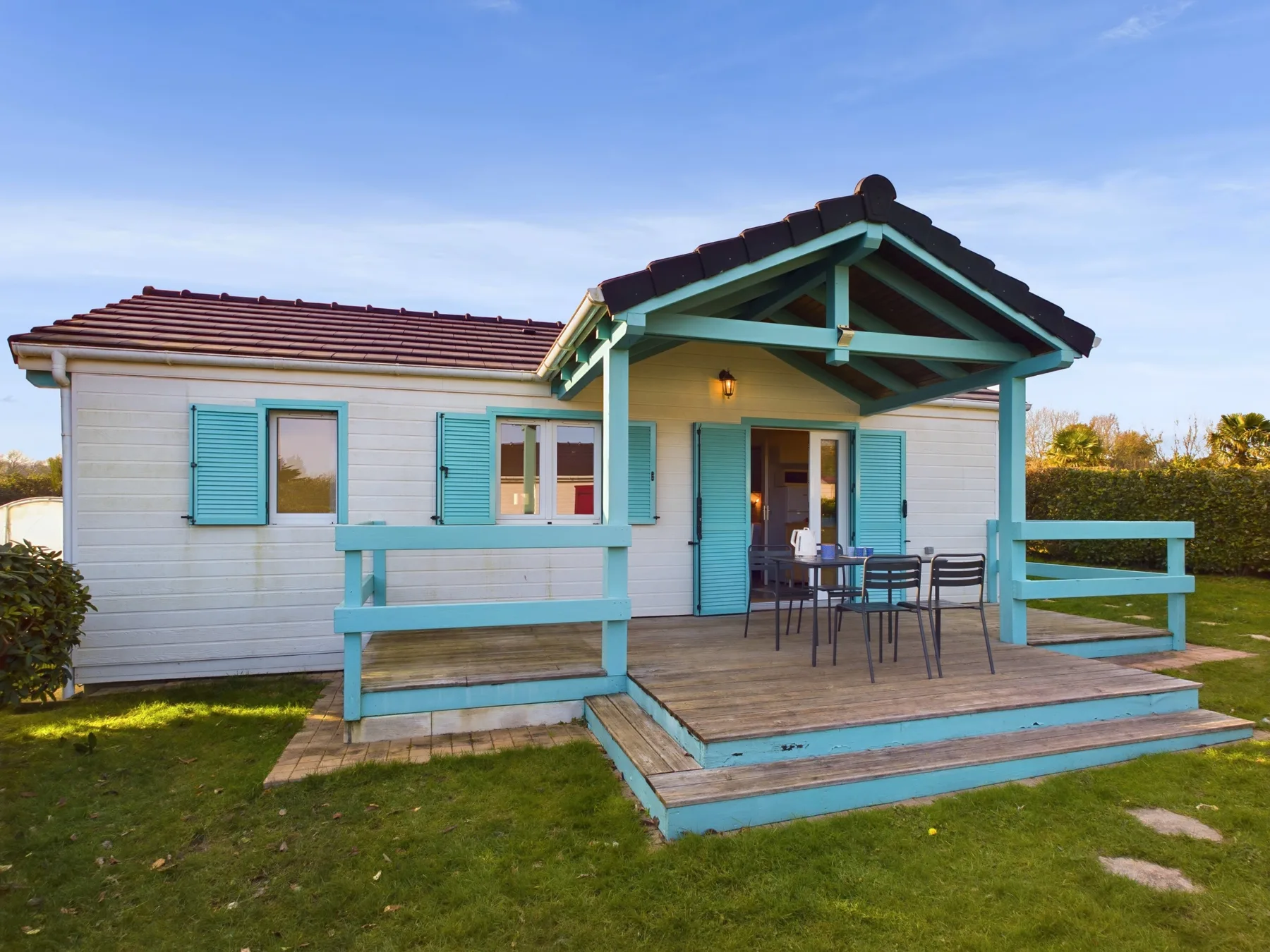 A bungalow with a covered porch and turquoise railings.