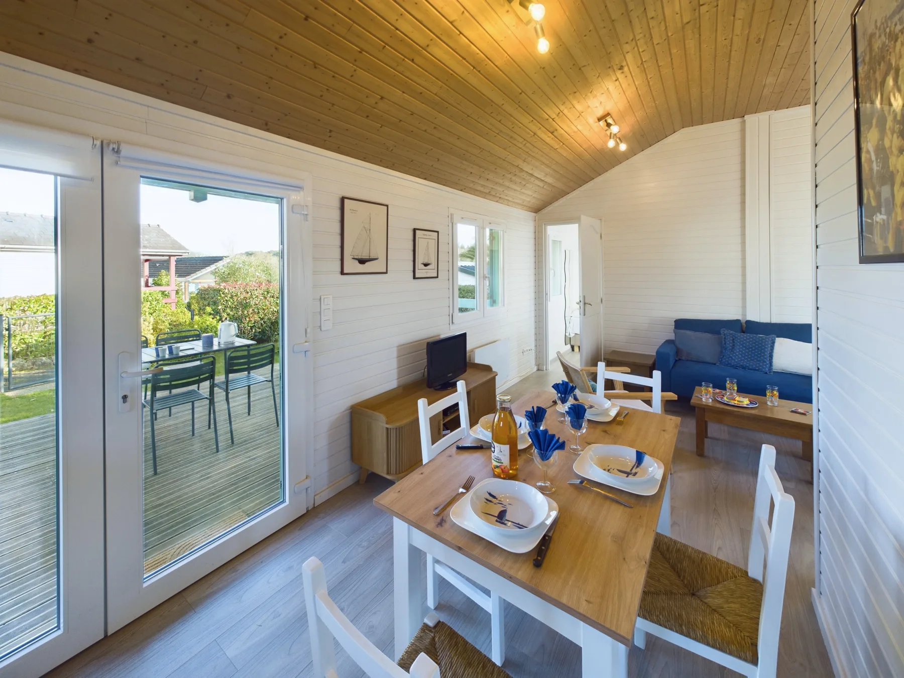 A bright dining and living area with a wooden table and blue seating.