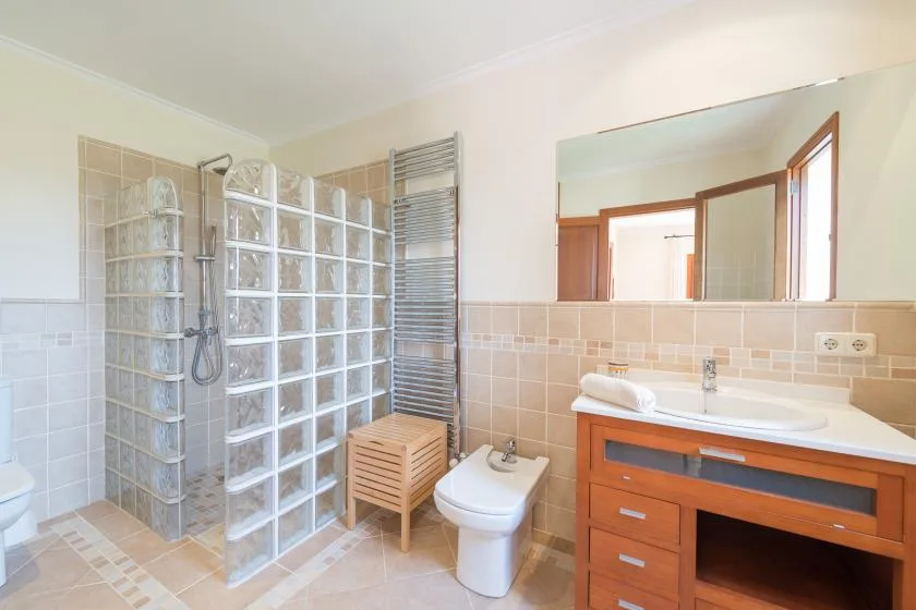 A bathroom with a glass shower, sink, and toilet.
