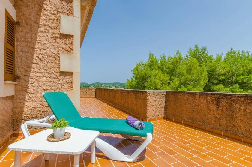 A sunlit terrace with a turquoise lounge chair and a small table.