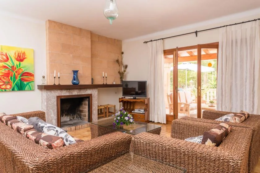 A living room with woven seating arranged around a fireplace and television.