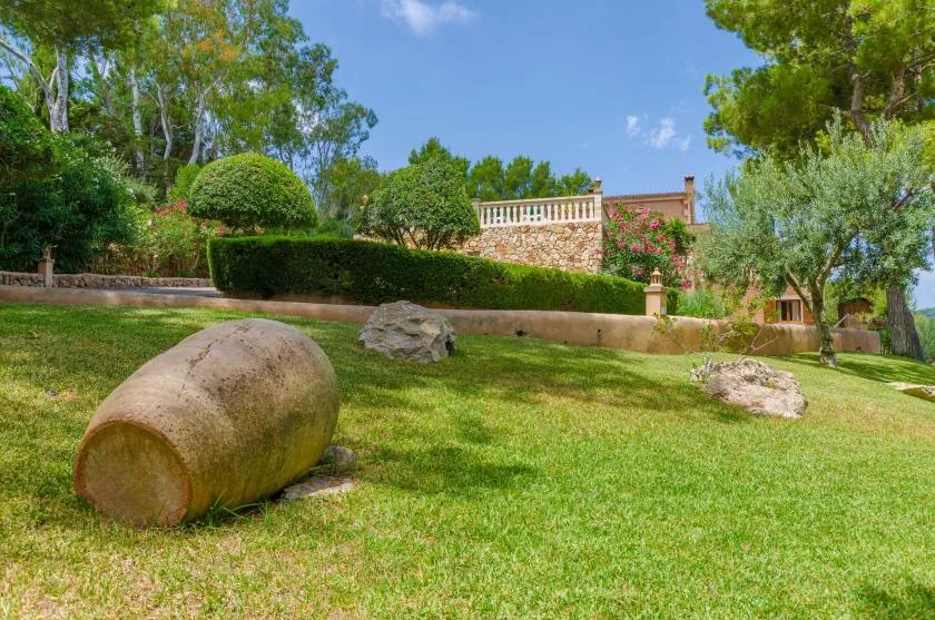 A landscaped garden with green lawn, trees, and large stone features.