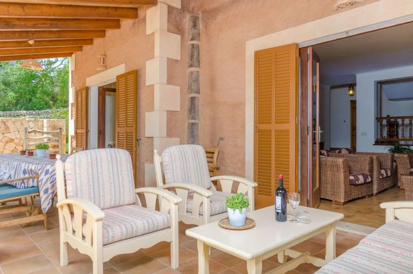 A covered patio with cushioned seating and open wooden shutters.