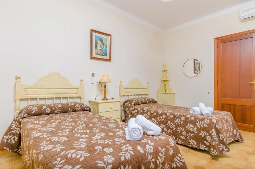 A bedroom with two beds covered in brown floral bedding.