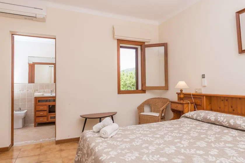 A bedroom with a patterned bedspread, bedside table, and open window.