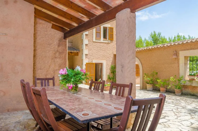 A covered outdoor dining area with a long table and wooden seating.